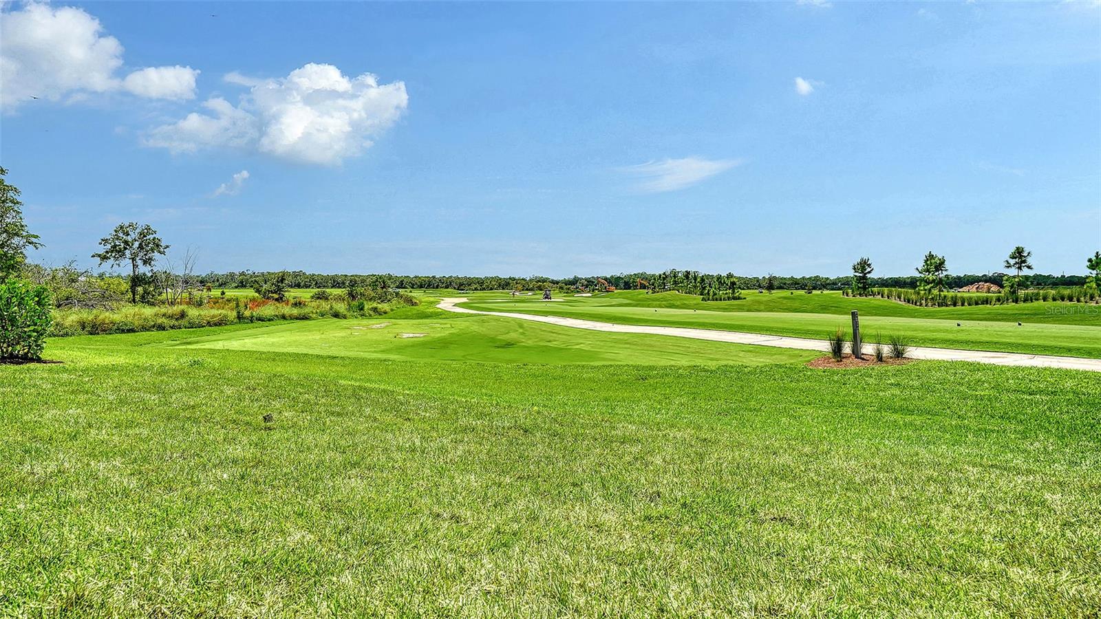 Green lawn overlooks rolling golf course fairways and a curving cart path.