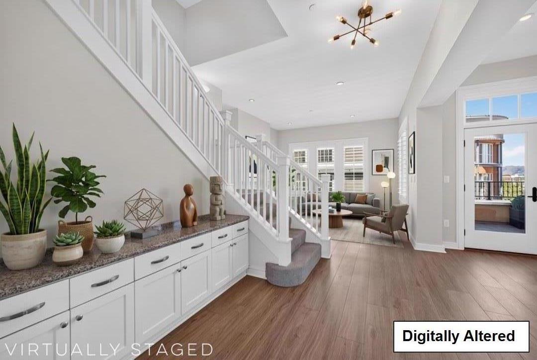 Bright staged living area with a white staircase, built-in cabinetry, and glass balcony doors.