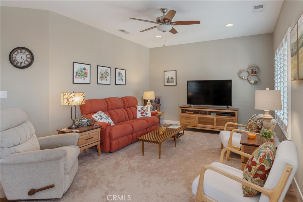 Living room with a red sofa, white armchairs, and a television on a wooden console.