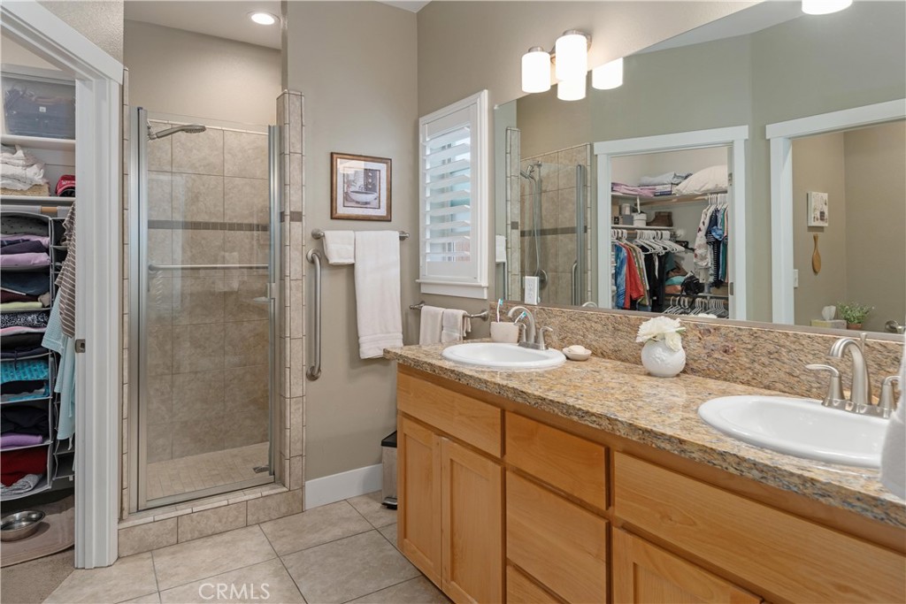 Bathroom with a long granite double vanity and glass-enclosed tiled shower.
