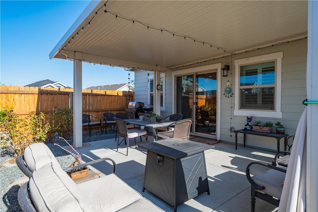 Covered patio with lounge and dining furniture, string lights, and a wooden privacy fence.