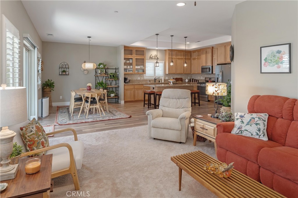 Open-plan living room with red sofa, dining area, and wood-cabinet kitchen.