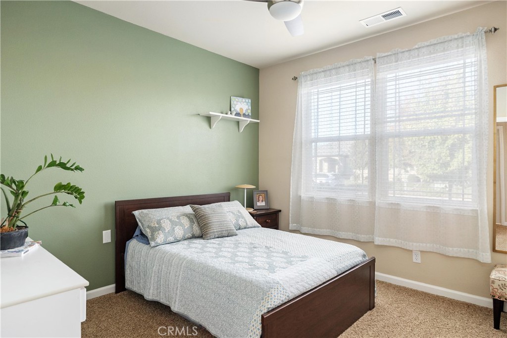 Bedroom with a dark wood bed, green accent wall, and large curtained windows.