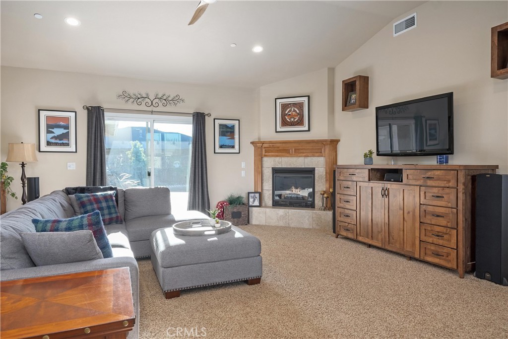 Living room with a gray sectional, fireplace, and wooden media console beside sliding glass doors.
