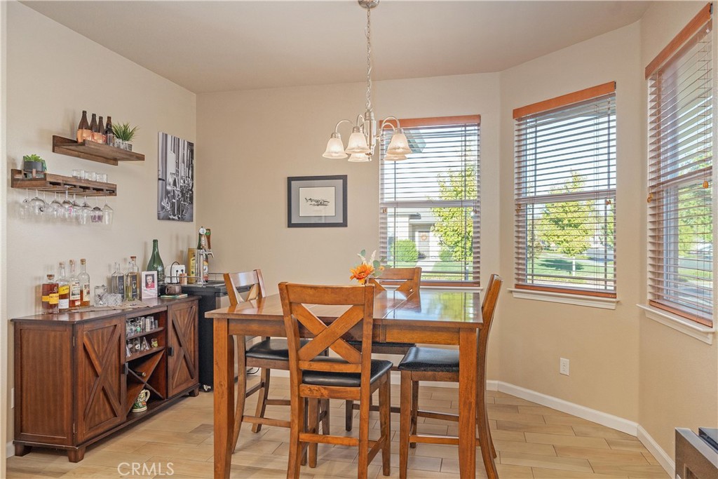 Dining room with a wooden table and chairs, bar sideboard, and three windows with blinds.