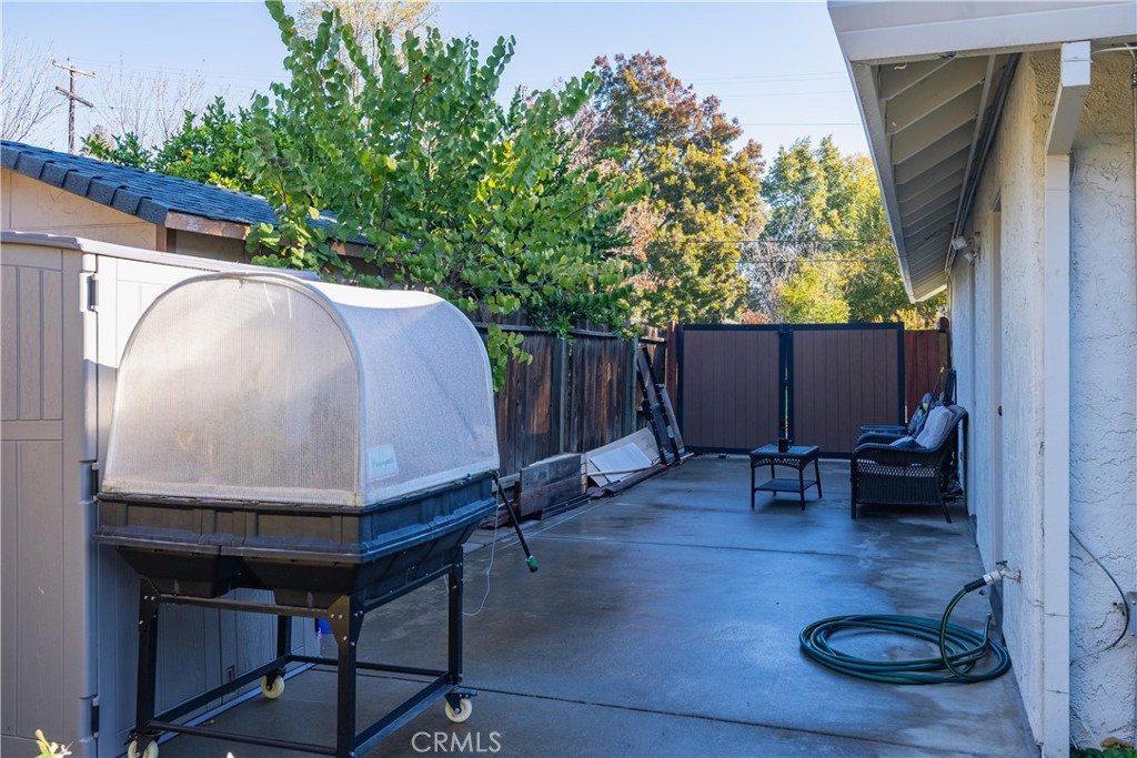 Paved patio with a covered raised tub, outdoor chairs, and a fenced yard.