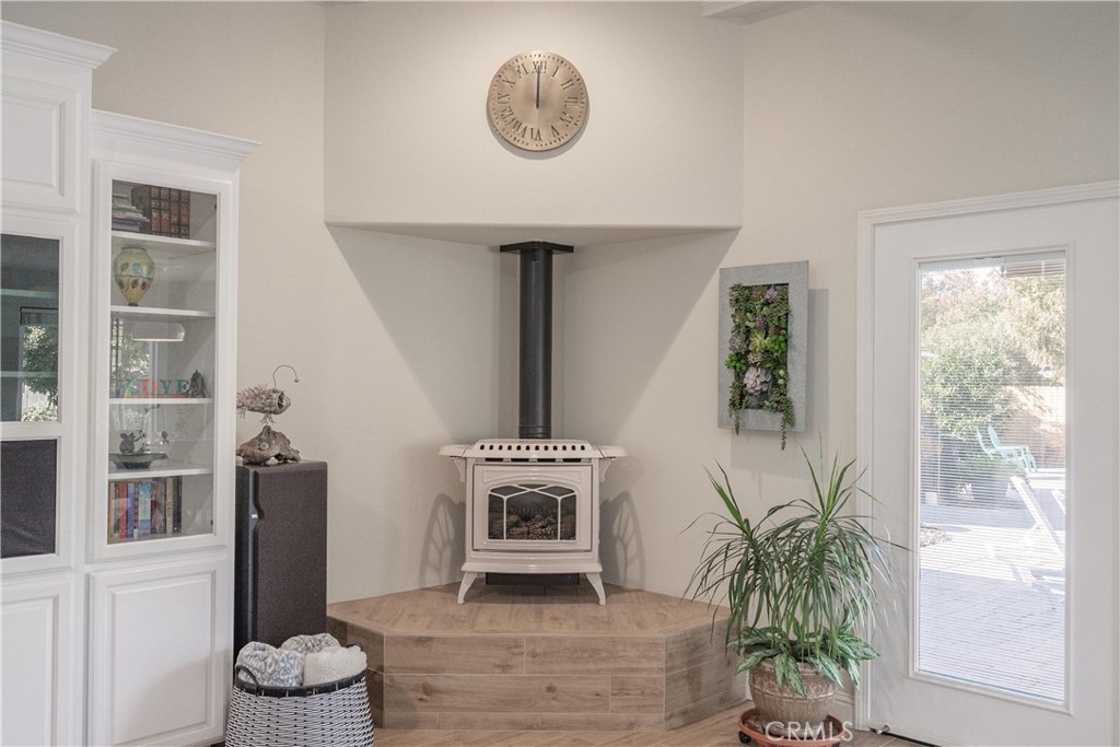 Living room stove on a raised tiled hearth beside built-in display cabinets and a glass door to the deck.