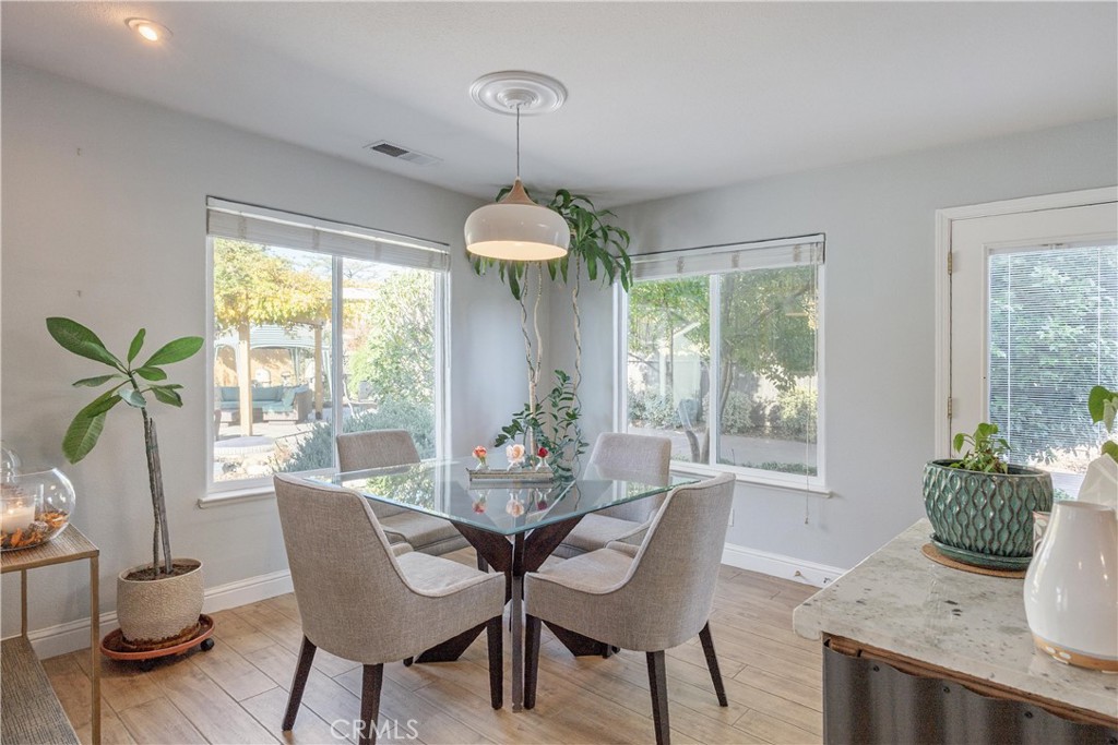 Dining room with a glass table, upholstered chairs, and large corner windows.