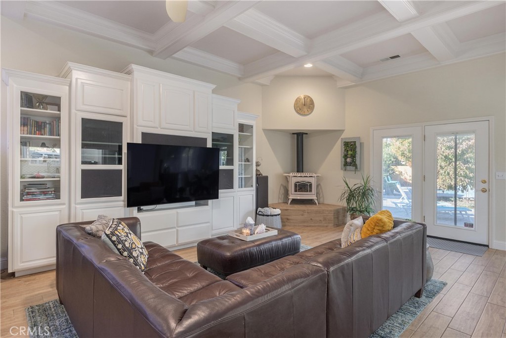Living room with white built-in cabinetry, a leather sectional, and a freestanding stove on a raised hearth.