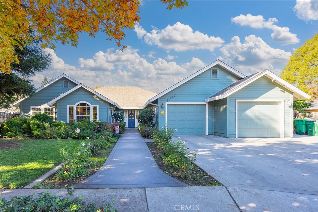 Blue home with two garage doors, a landscaped entry, and a curved walkway.