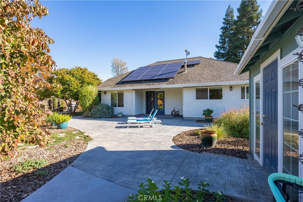 Rear patio with stamped-concrete paving, lounge chairs, and rooftop solar panels.