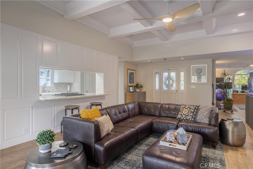 Living room with a leather sectional, coffered ceiling, and pass-through kitchen.