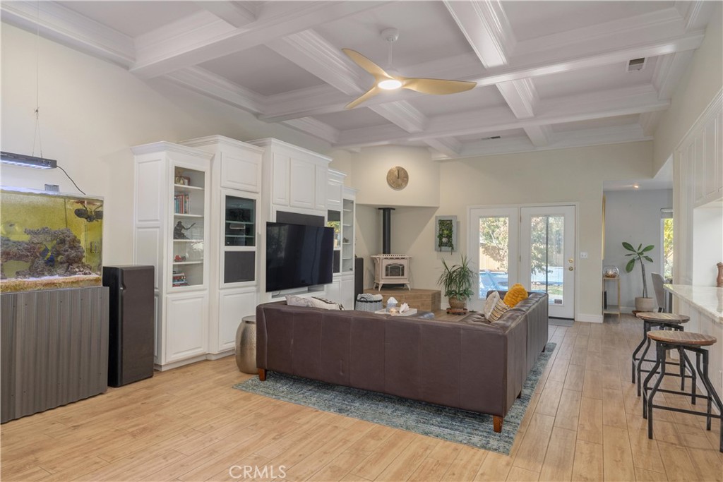 Living room with coffered ceiling, white built-ins, aquarium, and glass doors overlooking a pool.
