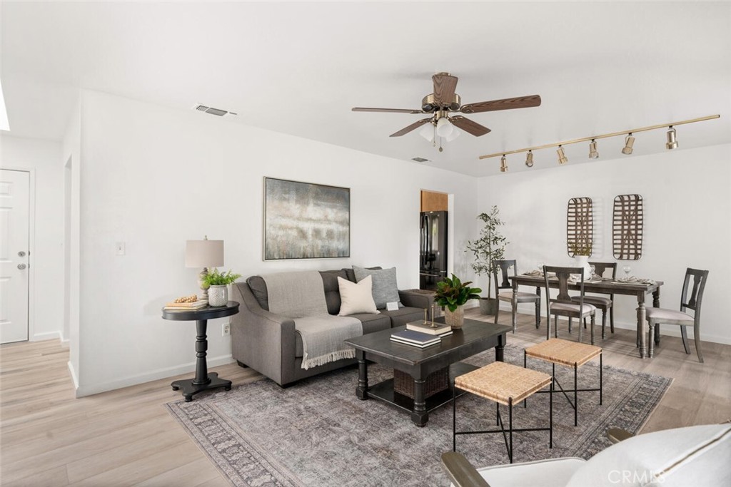 Open-plan living and dining room with a gray sofa, patterned rug, and dark dining table.