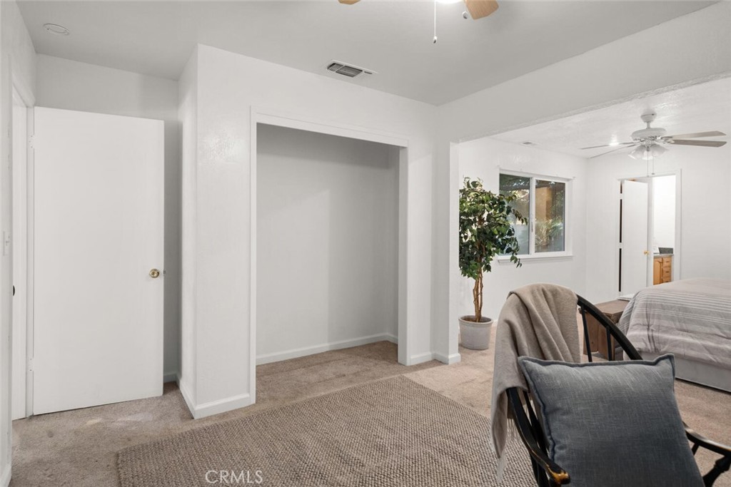 Staged bedroom with carpet, ceiling fans, a window, and an open alcove.