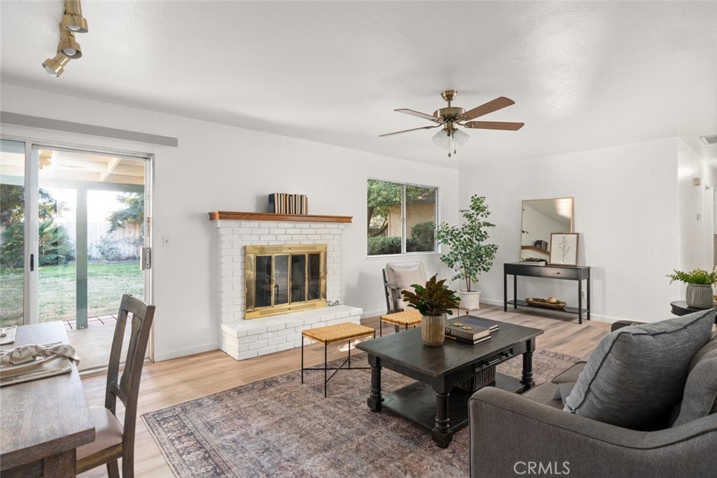 Furnished living room with a white brick fireplace, sliding glass doors, and wood flooring.