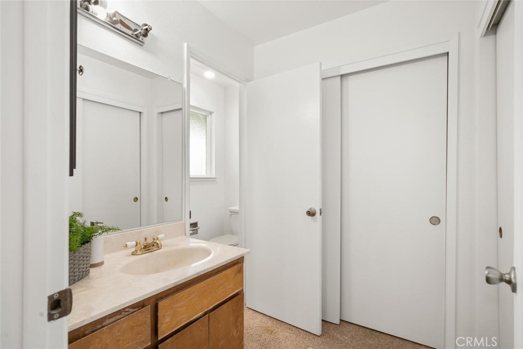 Bathroom with a wood vanity, large mirror, and white doors.