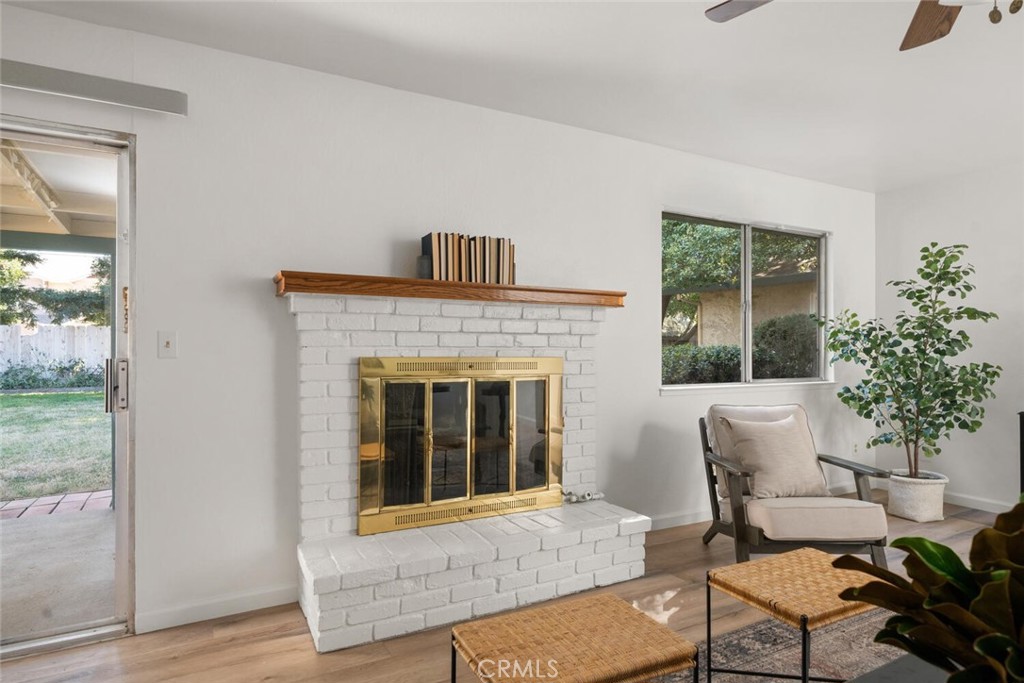 Living room with a white brick fireplace, brass doors, and a wood mantel.