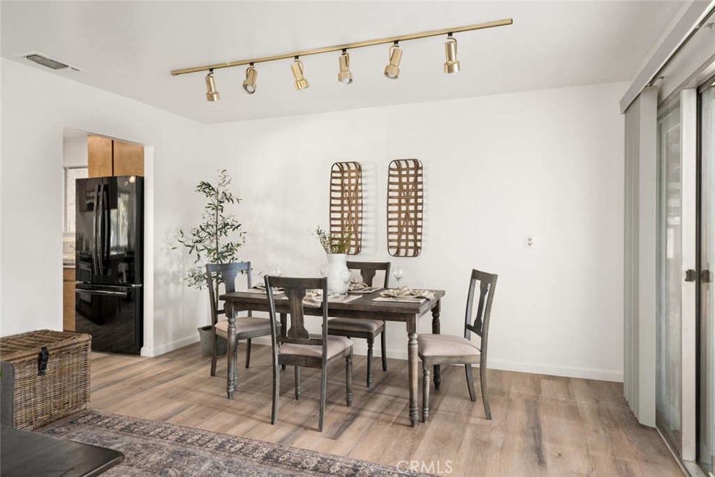 Furnished dining room with a dark wood table, track lighting, and sliding glass doors.