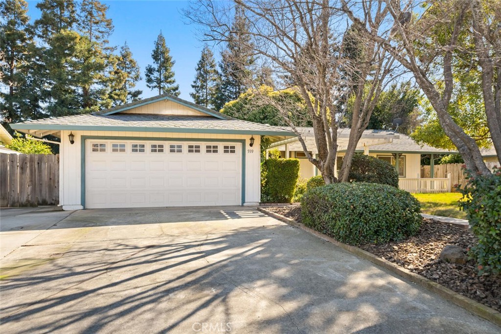 Single-story home with a two-car garage, broad driveway, and mature trees.