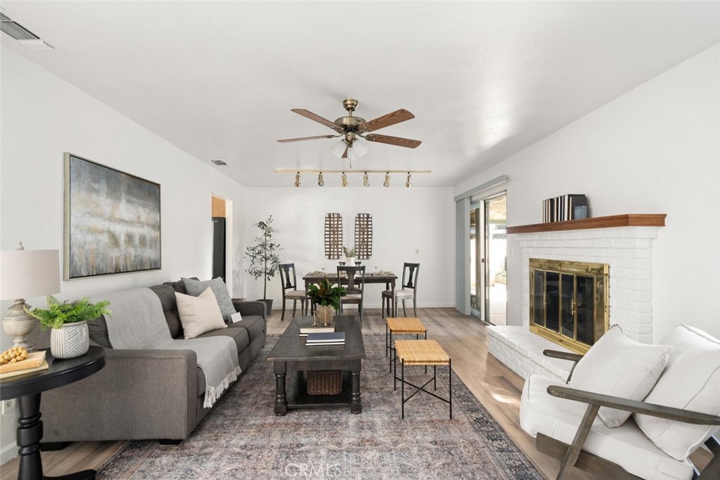 Living room with a gray sectional, dining table, and white brick fireplace.