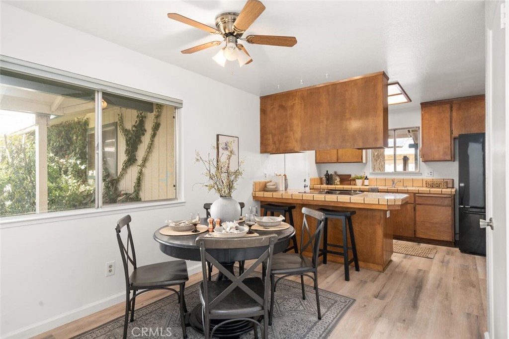 Kitchen and dining area with warm wood cabinets, a tiled breakfast bar, and a set dining table.