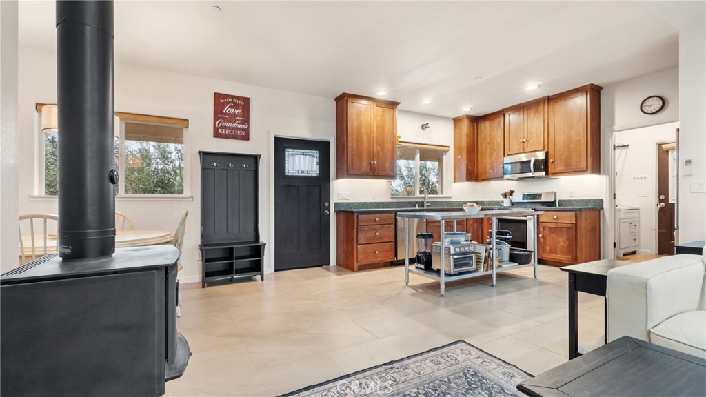 Open kitchen with warm wood cabinets, a rolling worktable, and a black freestanding wood stove.