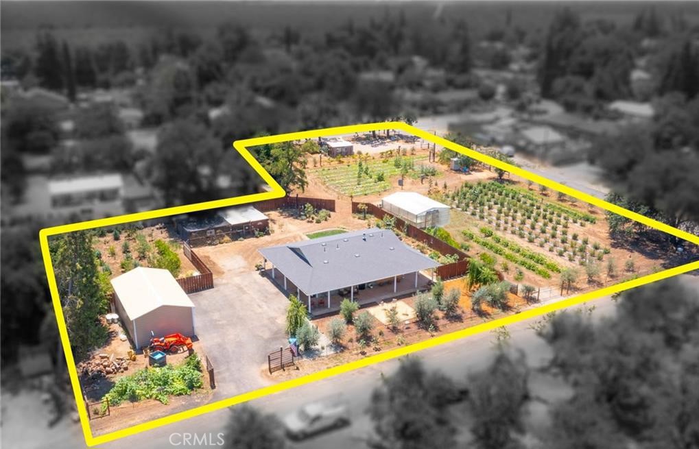 Aerial view of a home, outbuilding, greenhouse, and planted rows within a yellow parcel outline.