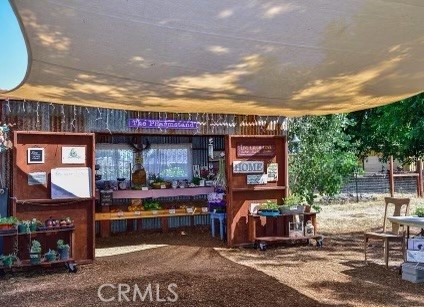 Covered outdoor display area with wooden shelves and counters beneath a large canopy.