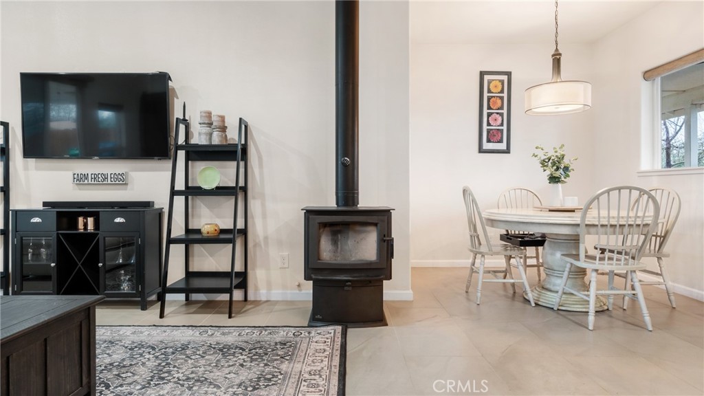 Living and dining area with a wood stove, television, and round farmhouse table.