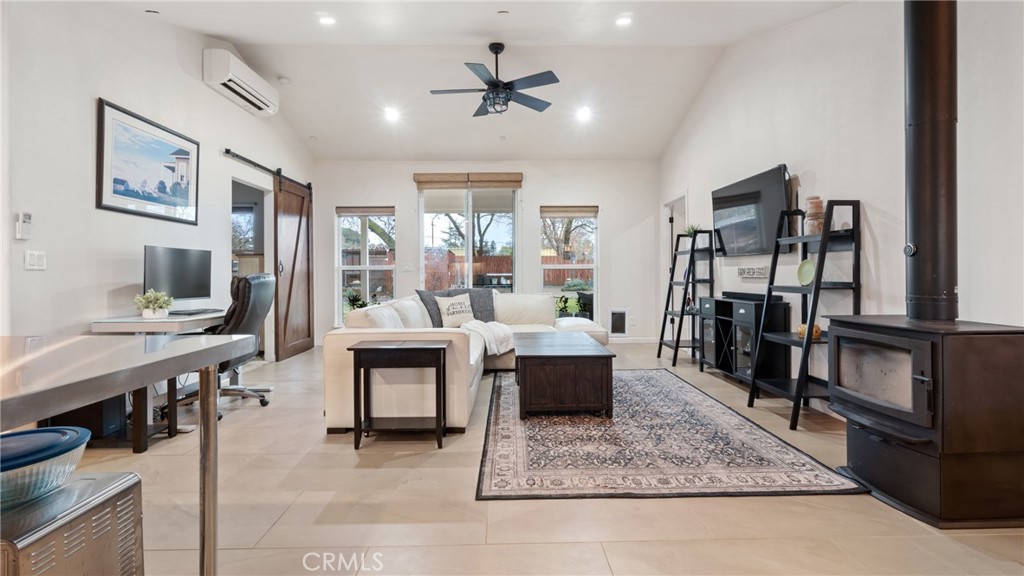 Living room with a white sectional, large windows, patterned rug, and black wood-burning stove.