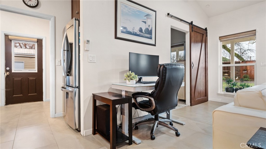 Home office with a desk and black chair beside a sliding barn door.