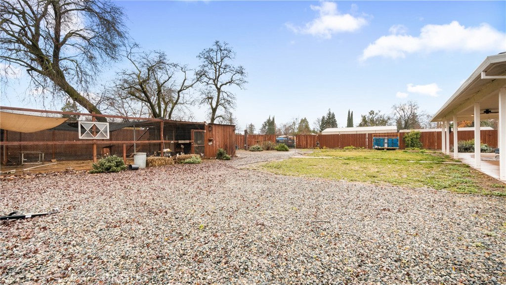 Backyard with a broad gravel area, wooden fencing, and a covered patio.