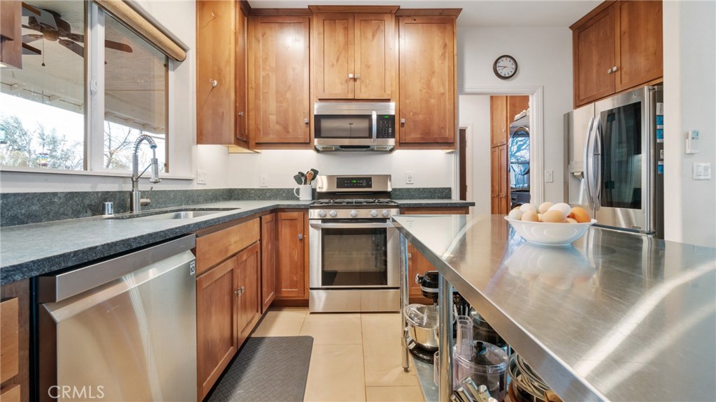 Kitchen with warm wood cabinets, stainless steel appliances, and a long island with a stone countertop.