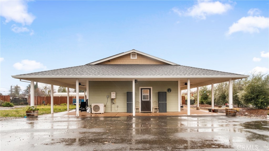 Single-story home with an expansive covered patio, white support posts, and wet paved driveway.