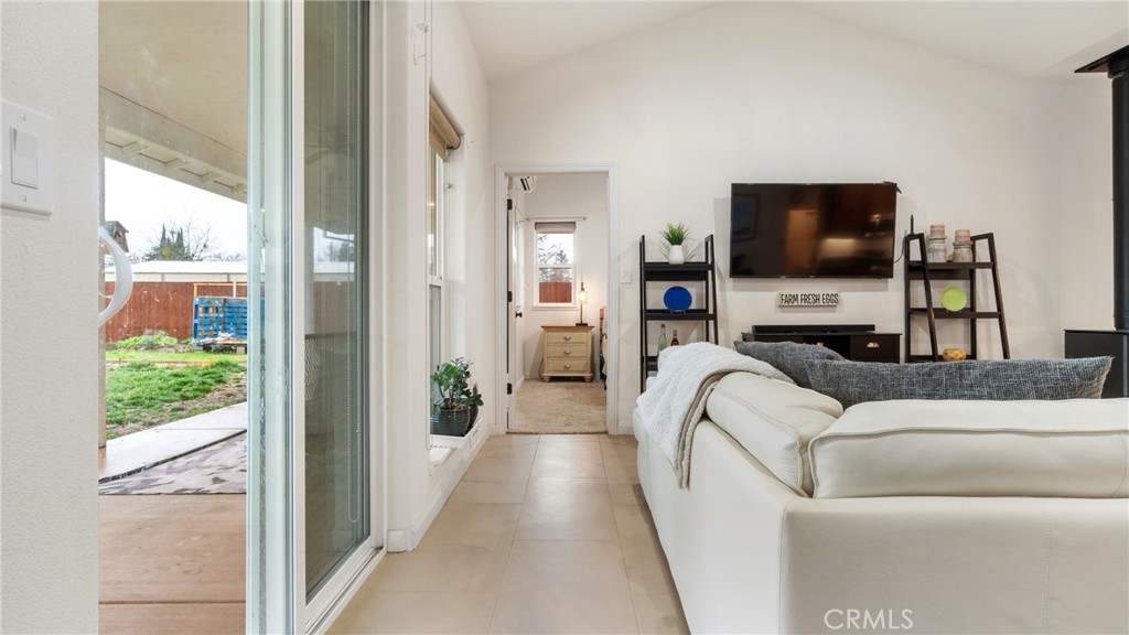 Living room with a white sectional, wall-mounted television, and sliding doors opening to the backyard.