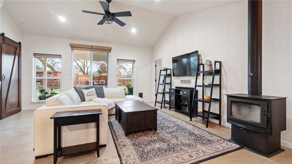 Living room with a white sectional, large yard-facing windows, and a black wood stove.