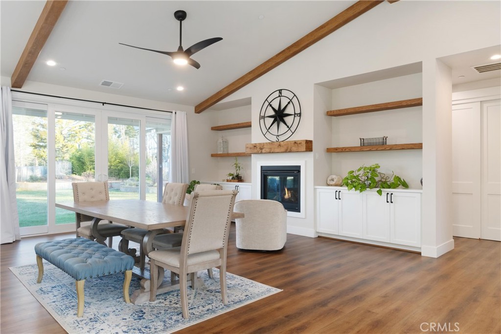 Dining area with a long table, blue tufted bench, fireplace, built-in shelves, and sliding glass doors to the yard.