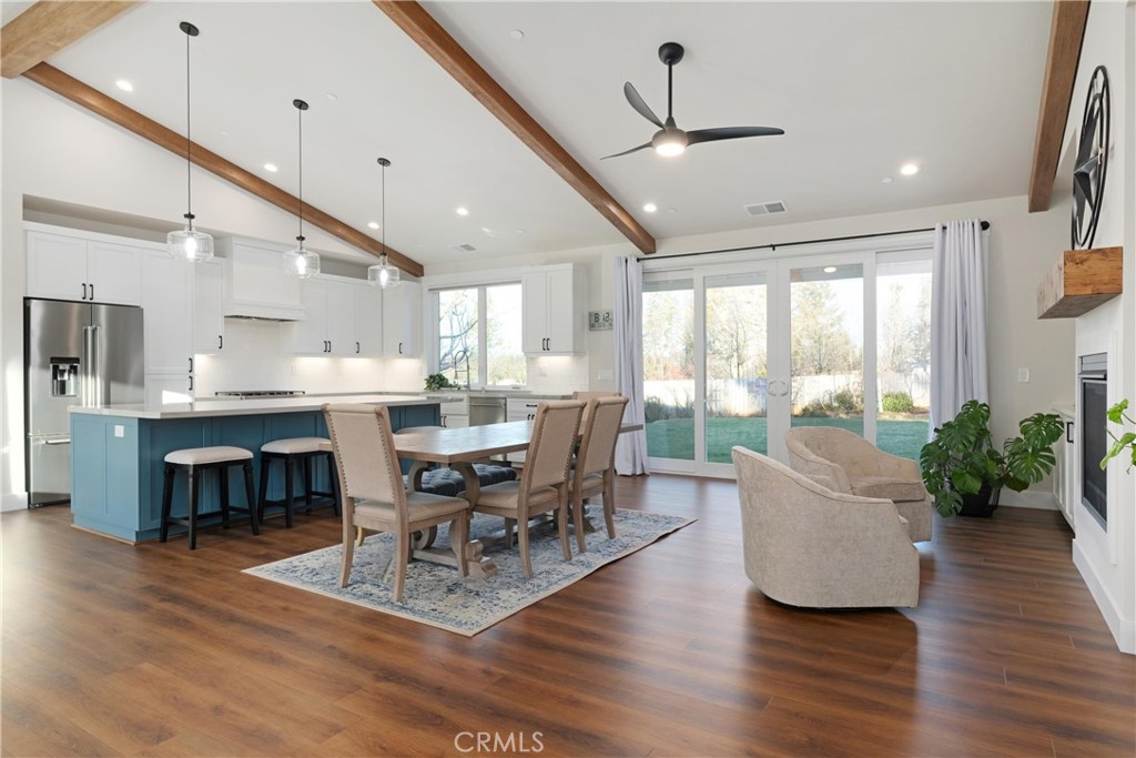 Open-plan kitchen and dining area with a blue island, exposed wood beams, and sliding glass doors to the yard.