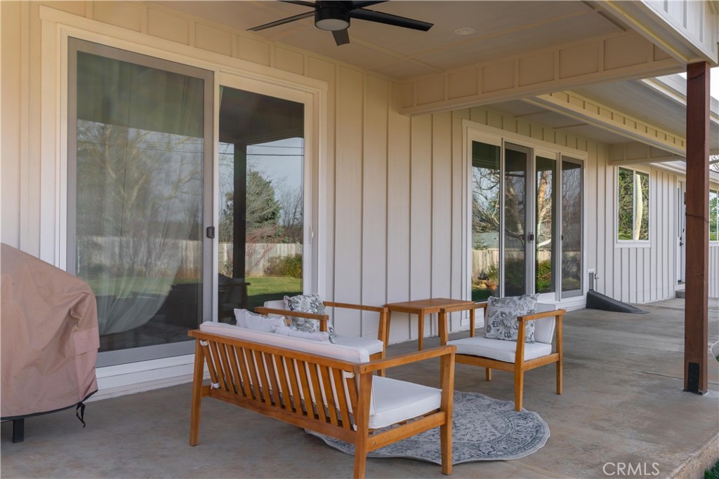 Covered patio with wooden seating, sliding glass doors, and a ceiling fan.
