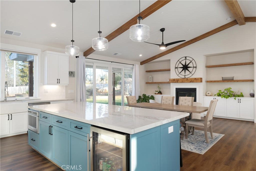 Kitchen with a large blue island, white stone counters, wood ceiling beams, and an adjoining dining area.