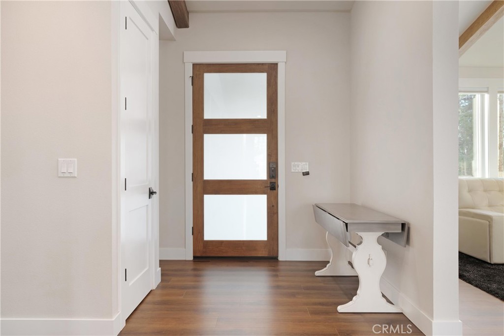 Entryway with a wood-framed frosted-glass door, warm wood flooring, and a white console table.