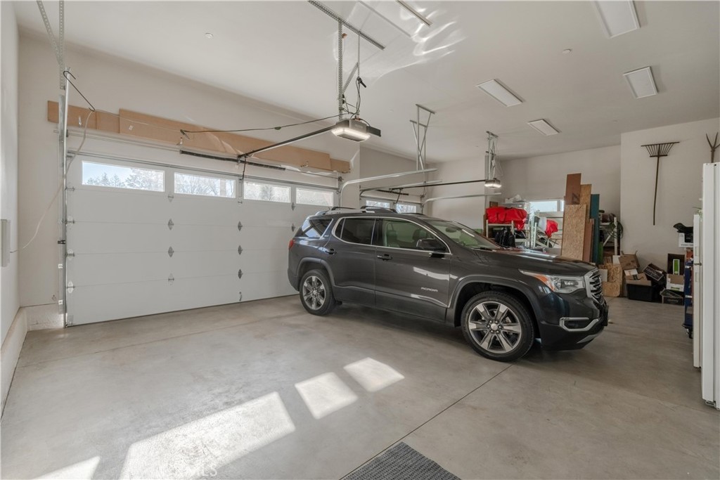 Spacious garage with a gray SUV, large garage door, and storage along the back wall.