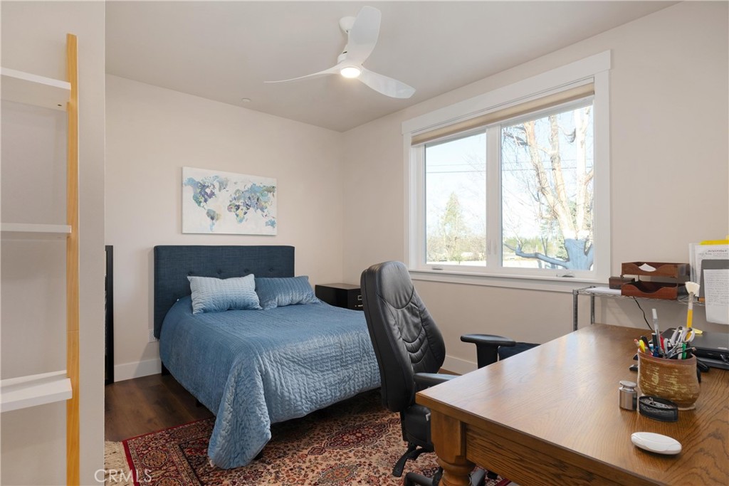 Bedroom and home office with a blue bed, wooden desk, and large window.