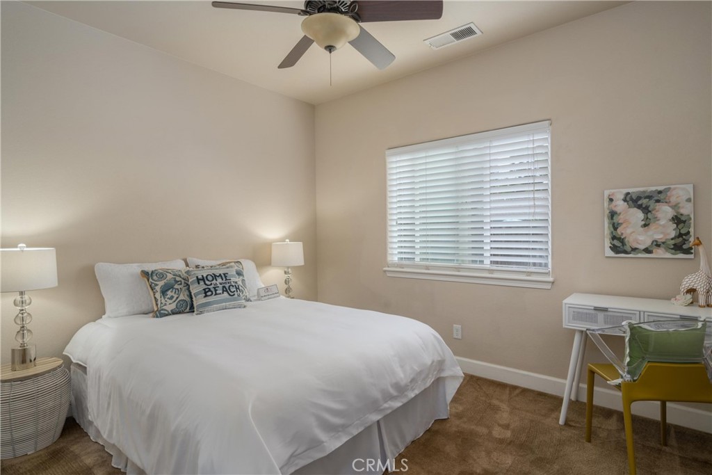 Bedroom with a white bed, ceiling fan, carpet, and a window with white blinds.