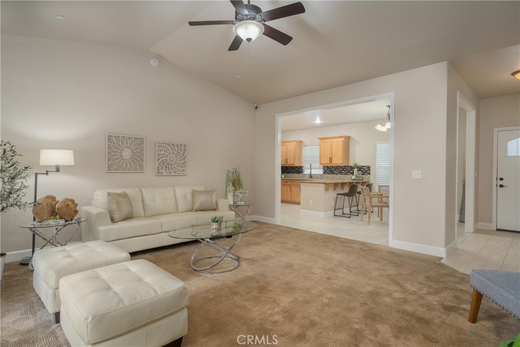Living room with white leather seating, a glass coffee table, and an open view into the kitchen.