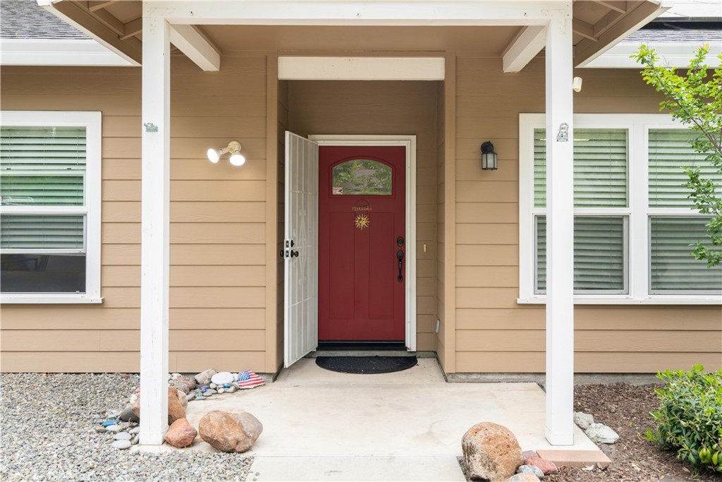 House entrance with a red front door, white porch posts, and a concrete walkway.