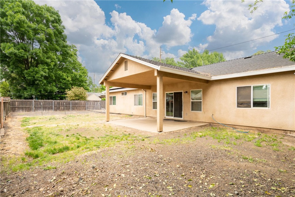 Home’s rear exterior with a covered patio and fenced yard.