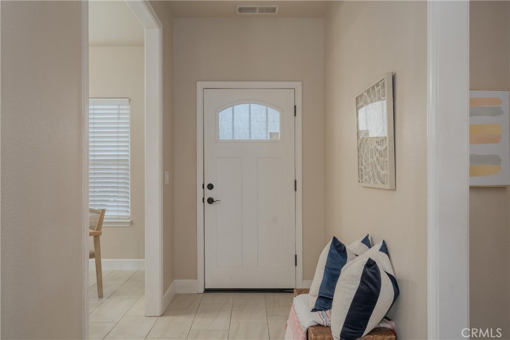 Entryway with a white arched-window front door and a woven bench with navy-and-white pillows.