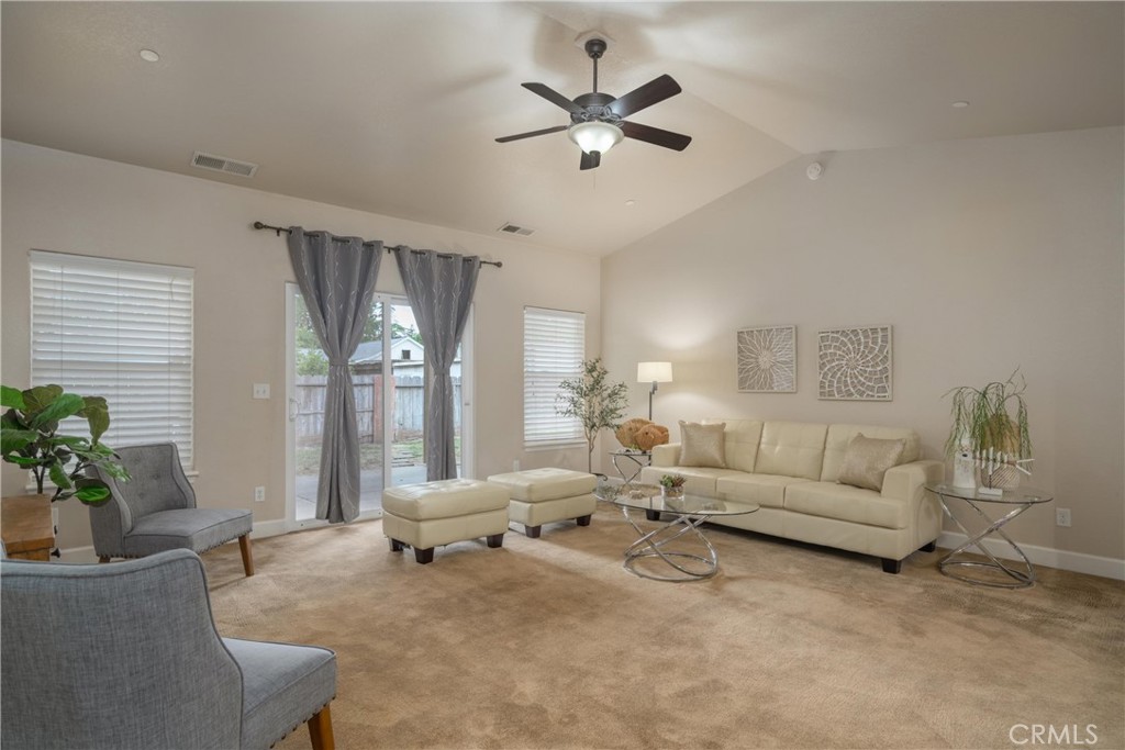 Staged living room with a cream sectional, glass coffee table, and sliding doors to a fenced yard.